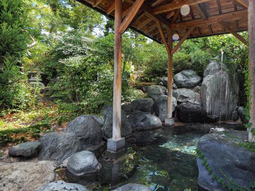 a pond with a wooden gazebo and rocks at Yatsusankan Over 6 years old in Hida