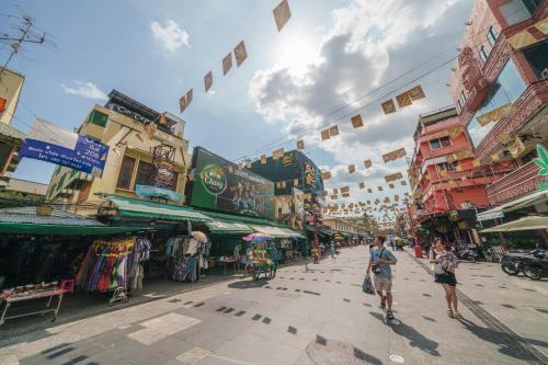 a group of people walking down a street with buildings at Dancenter Khaosan Park Hotel in Bangkok