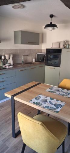 une cuisine avec une table en bois et deux chaises jaunes dans l'établissement Gîte ramloc, à Colmar