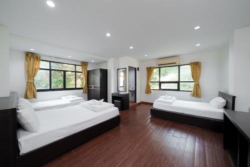a bedroom with two beds and two windows at Dancenter Khaosan Park Hotel in Bangkok