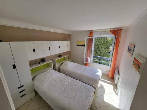une chambre avec deux lits et une fenêtre dans l'établissement Beach 5 mins walk,Wi-fi,AC,Pool,Parking,Elevator, à Fréjus