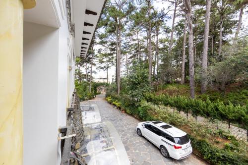 a white car parked on a road with trees at TTR Joy Apart' Hotel in Da Lat