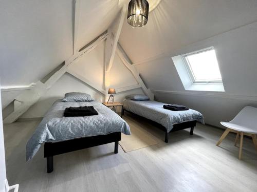 a attic bedroom with two beds and a window at Augustin's house in Héricy