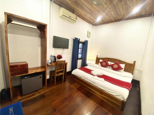 a bedroom with a bed and a desk and a television at Luangprabang That Luang Boutique House in Luang Prabang