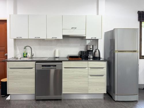 a kitchen with white cabinets and a stainless steel refrigerator at Tropical 2 Bedroom Pool House In Central Location in Hua Hin