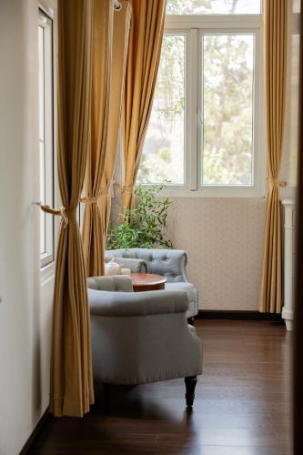 a living room with curtains and a chair and a table at TTR Joy Apart' Hotel in Da Lat