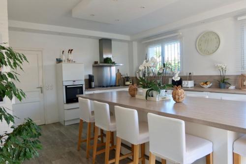 une cuisine avec une grande table en bois et des chaises blanches dans l'établissement Maison F5 piscine, à Saint-Cyprien