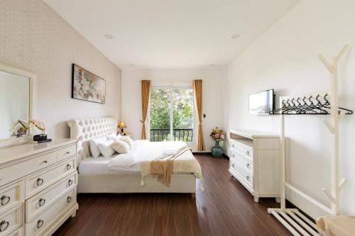 a bedroom with a white bed and a window at TTR Joy Apart' Hotel in Da Lat