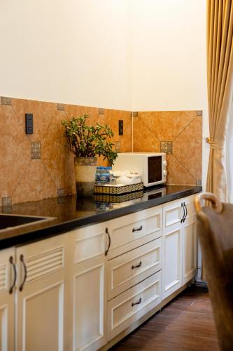 a kitchen with white cabinets and a sink and a microwave at TTR Joy Apart' Hotel in Da Lat