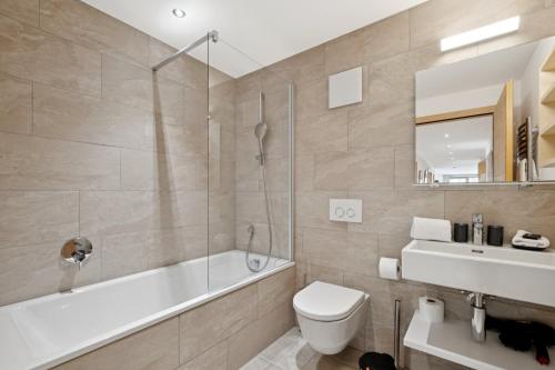 a bathroom with a tub and a toilet and a sink at Chalet Les Rahâs by Mrs Miggins in Grimentz