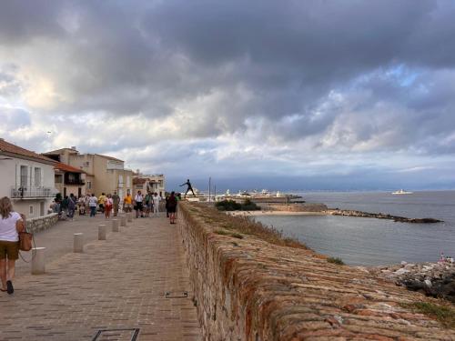 Un groupe de personnes marchant le long d'un mur près de l'eau dans l'établissement Location, à Antibes