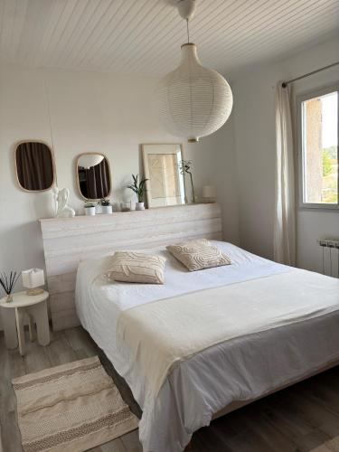 - une chambre blanche avec un grand lit et deux miroirs dans l'établissement Charmante maison en Provence, à Châteaurenard