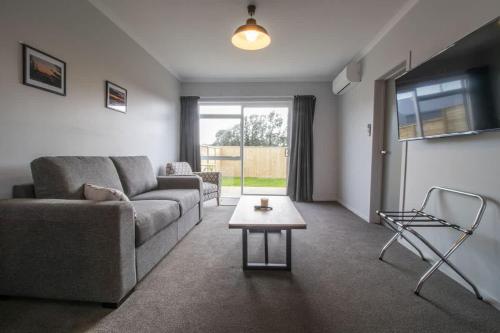 a living room with a couch and a table at The Window Seat - pet-friendly 1BR apartment in Waitara
