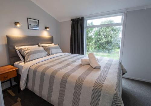 a bedroom with a bed with a large window at The Window Seat - pet-friendly 1BR apartment in Waitara