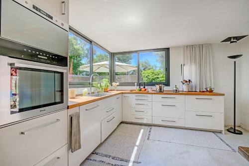 une cuisine avec des placards blancs et une grande fenêtre dans l'établissement Antibes Loft Retreat - Happy Rentals, à Juan-les-Pins