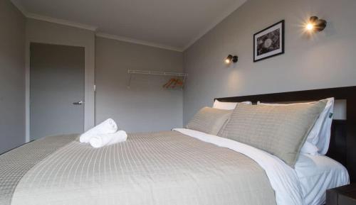 a bedroom with a bed with white sheets and pillows at The Aisle Seat - pet-friendly 1BR modern apartment in Waitara
