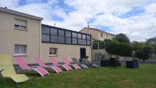 a row of chairs sitting in the grass in front of a building at Gîte Chez Gwen et Flo avec Jardin in Cholet