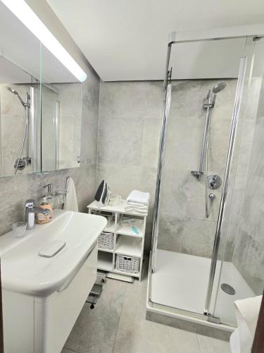 a white bathroom with a shower and a sink at Apartment Rose in Forbach