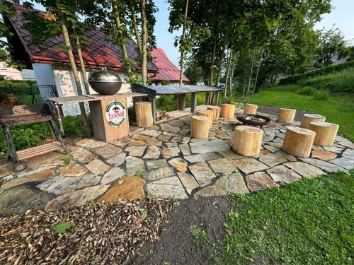 a stone patio with a grill and wooden stools at Apartmány U Šťastných in Cerny Dul
