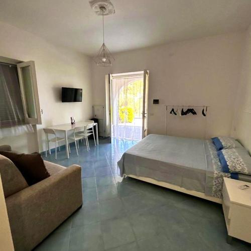 a bedroom with a bed and a couch and a table at Maison Emi in Montecorice