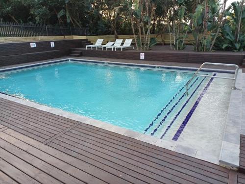 a swimming pool with two chairs and a wooden deck at Sodwana Bay Lodge House 58 in Sodwana Bay