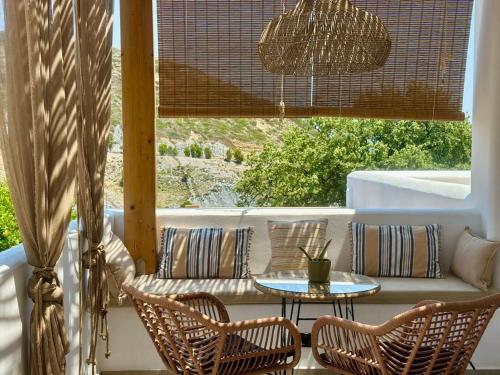 a porch with a couch and chairs and a table at Apademia Skyros Luxury Residences in Skiros
