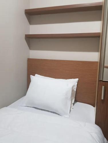 a white bed with a wooden headboard and white pillows at Jardin B20, Pool View, Netflix & WIFI in Bandung