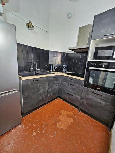 une cuisine avec des appareils en acier inoxydable et du carrelage rouge au sol dans l'établissement Jean - 2 chambres dans le centre historique - WIFI -, à Avignon