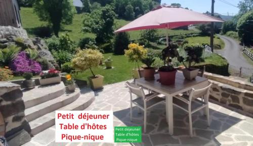 a table with an umbrella and potted plants at un petit coin paisible in Le Monteil