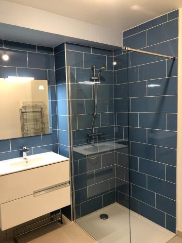 La salle de bains est pourvue de carrelage bleu, d'une douche et d'un lavabo. dans l'établissement Studio 38m2 le Grand Angle, centre-ville, parking et terrasse, à Aix-les-Bains