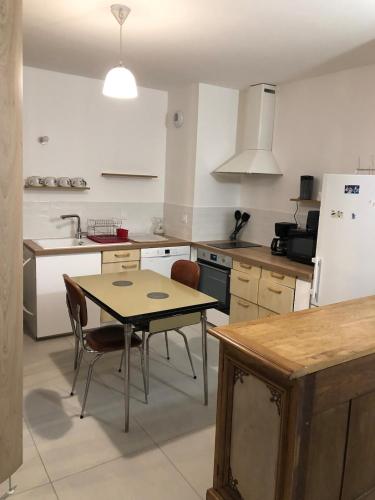 Il comprend une cuisine équipée d'une table, d'une table et d'un réfrigérateur. dans l'établissement Studio 38m2 le Grand Angle, centre-ville, parking et terrasse, à Aix-les-Bains