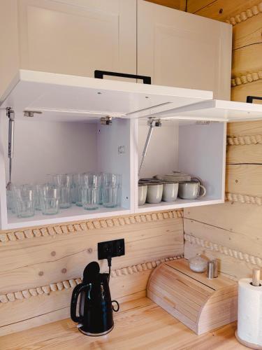 a kitchen with a cupboard with bowls and utensils at Świerkowe Chatki w Koniakowie in Koniaków
