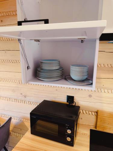 a black microwave sitting on a table with plates at Świerkowe Chatki w Koniakowie in Koniaków