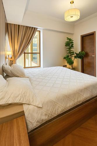 a large white bed in a bedroom with a window at New Luxe 2 BR in Dubai