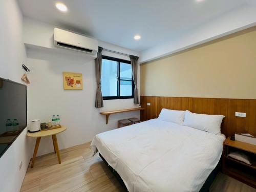 a bedroom with a white bed and a television at 有某行旅 yóu mǒu hostel in Tainan
