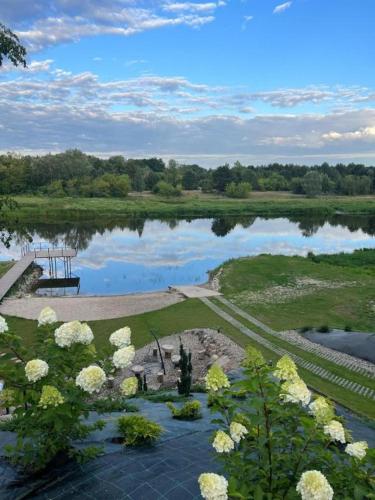 a view of a lake with a bench and flowers at Relax nad Narwią u Oli I Pawła in Pultusk