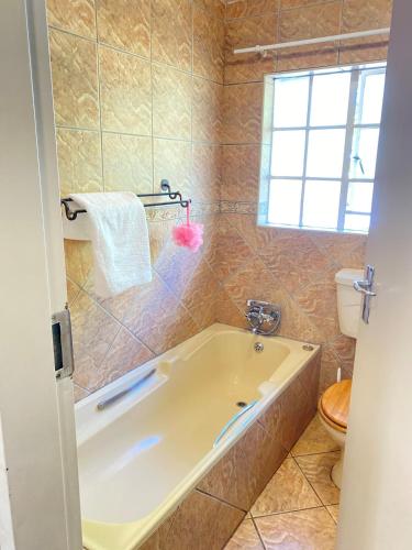 a bathroom with a tub and a toilet and a window at Cosy Room steps from the lake in Benoni