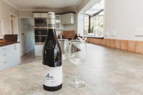 a bottle of wine sitting next to a wine glass at Family Fun - 4BR home with swimming pool and spa in New Plymouth