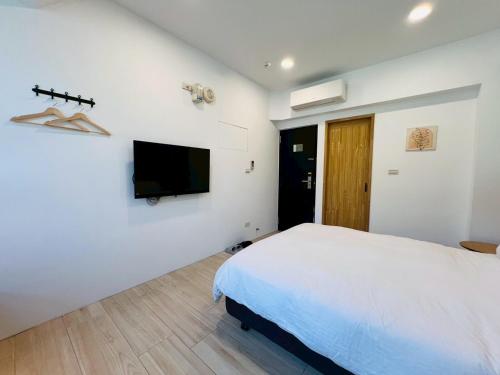 a bedroom with a bed and a tv on a wall at 有某行旅 yóu mǒu hostel in Tainan