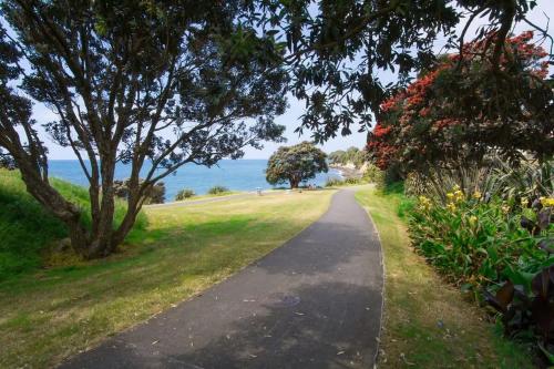 a path through a park with trees and flowers at Blue Haven On Belt - seconds to coastal walkway in New Plymouth