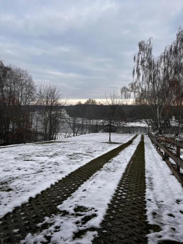 a snow covered path in a field with a fence at Relax nad Narwią u Oli I Pawła in Pultusk