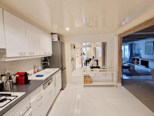 une cuisine avec des armoires blanches et une personne en arrière-plan dans l'établissement Marais Design flat, à Paris