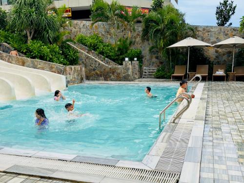 un groupe de personnes nageant dans une piscine dans l'établissement CONDOTEL APEC Mũi Né, à Ấp Thiẹn Ái