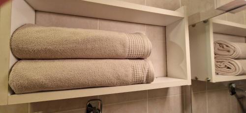 - une pile de serviettes sur une étagère dans une salle de bains dans l'établissement Bleues Marines studio piscine, à Antibes