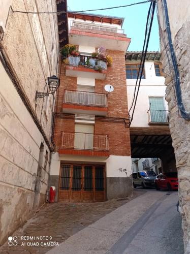 a brick building with a balcony on a street at Apartamento Benabarre Huesca in Benabarre