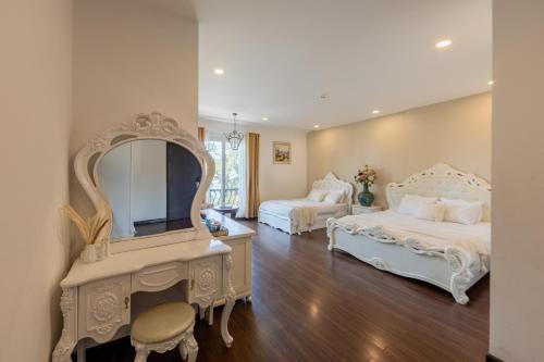a bedroom with two beds and a vanity and a mirror at TTR Joy Apart' Hotel in Da Lat