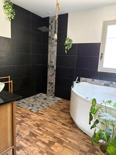 La salle de bains est pourvue d'une baignoire blanche et de carrelage noir. dans l'établissement La Villa Détente, à Saint-Vincent-de-Tyrosse