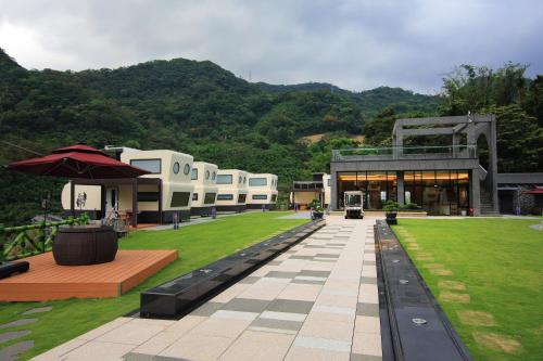 a building with a green lawn and a building with an umbrella at Secret Silva in Sanxia