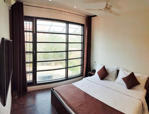 a bedroom with a bed and a large window at The Wind Cross in Kālka