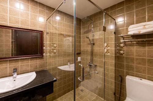 a bathroom with a glass shower and a sink at TTR Joy Apart' Hotel in Da Lat